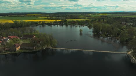 Amazing-flight-with-a-chimelice-plzen-bohemia-bird-over-water,-green-fields-in-the-horizon