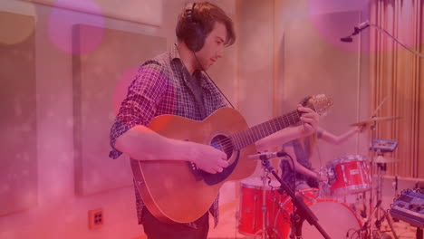 bandmates playing acoustic guitar and drums in recording studio, with animated sound waves overlay
