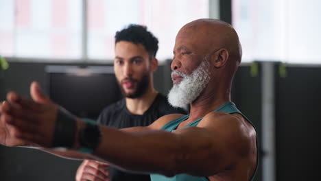 fitness trainer assisting senior man in workout