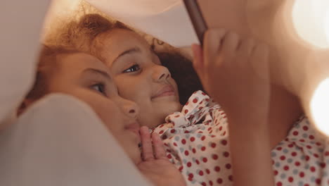 mixed-race girls using tablet in pillowfort