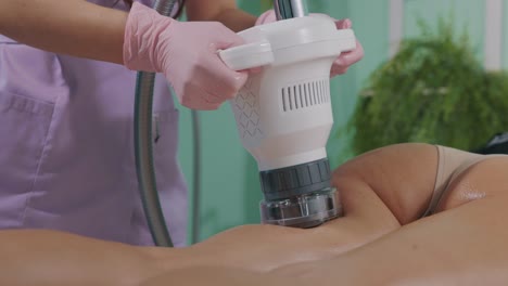 esteticista en una sesión de adelgazamiento con instrumento de cavitación al vacío en un salón de belleza