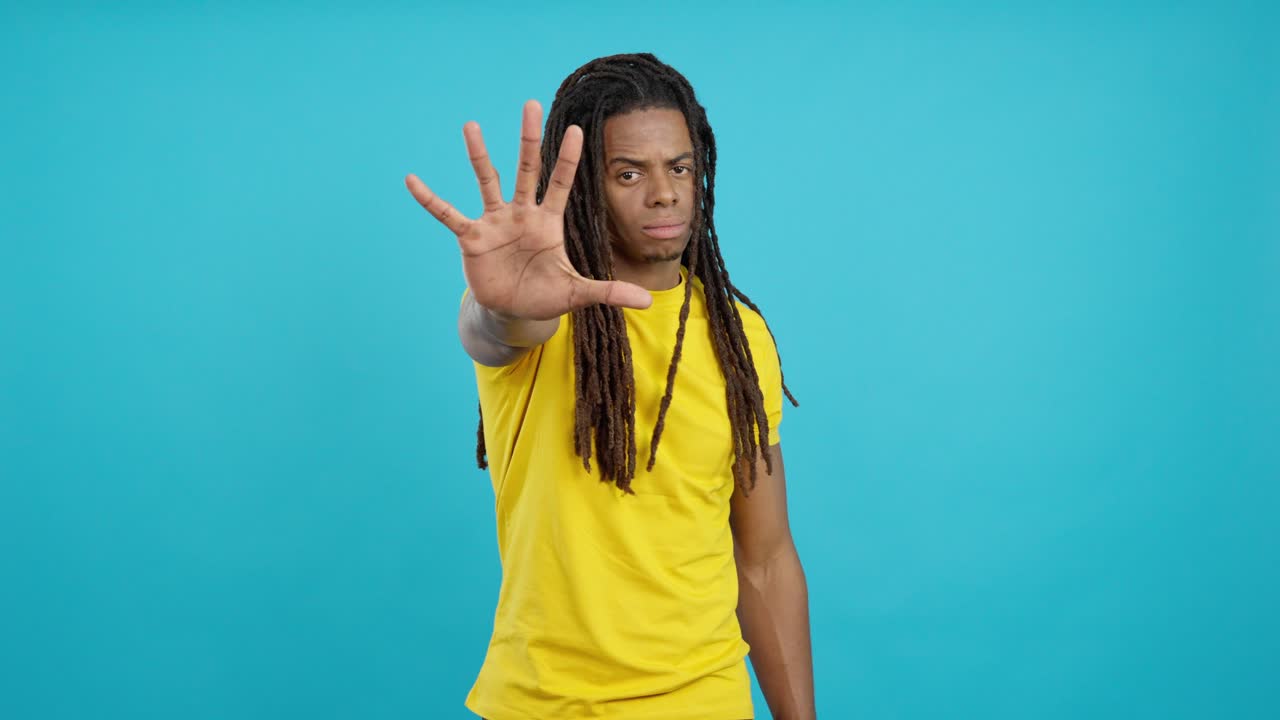 Man with dreadlocks holding up hand