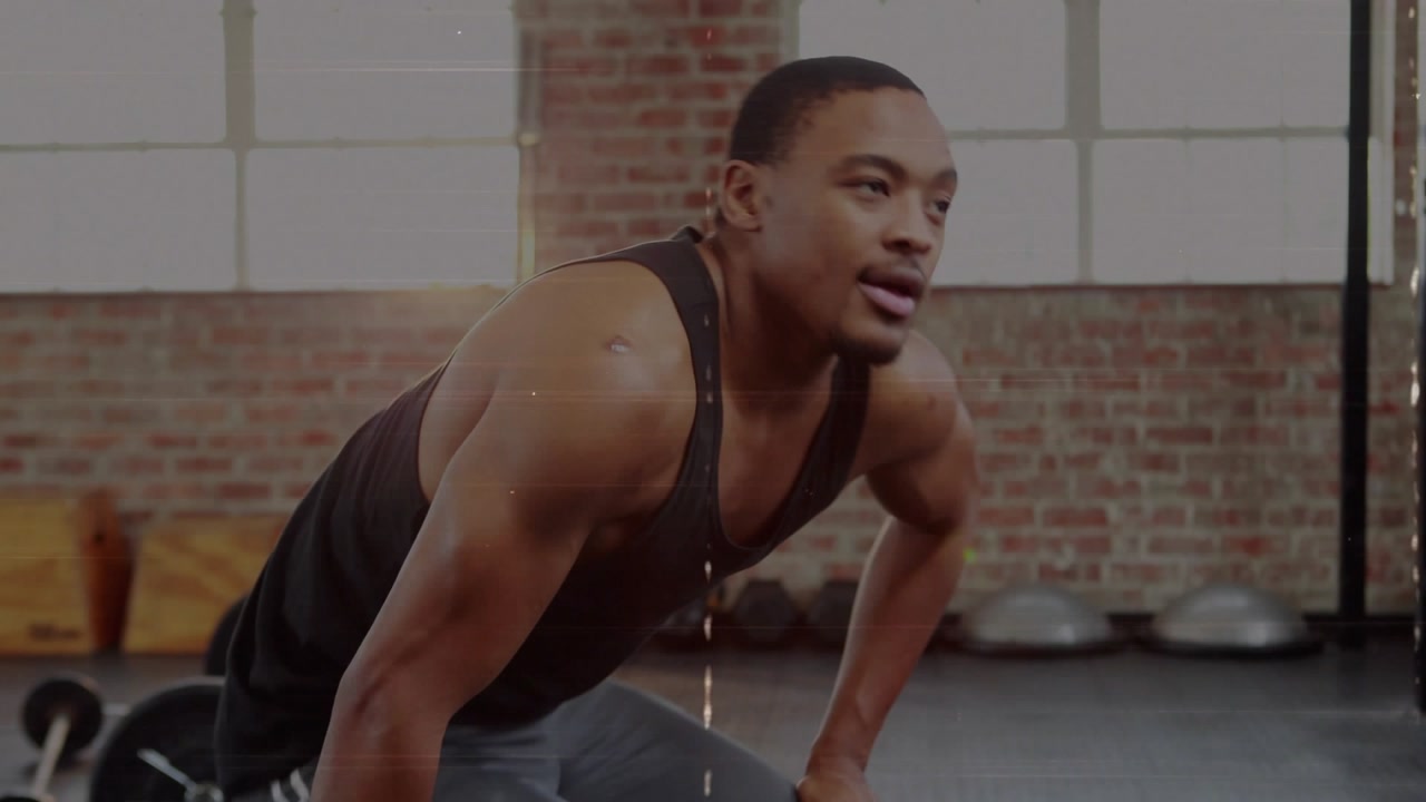 Man bracing left hand and initiating one-arm dumbbell rows in fitness studio, building strength