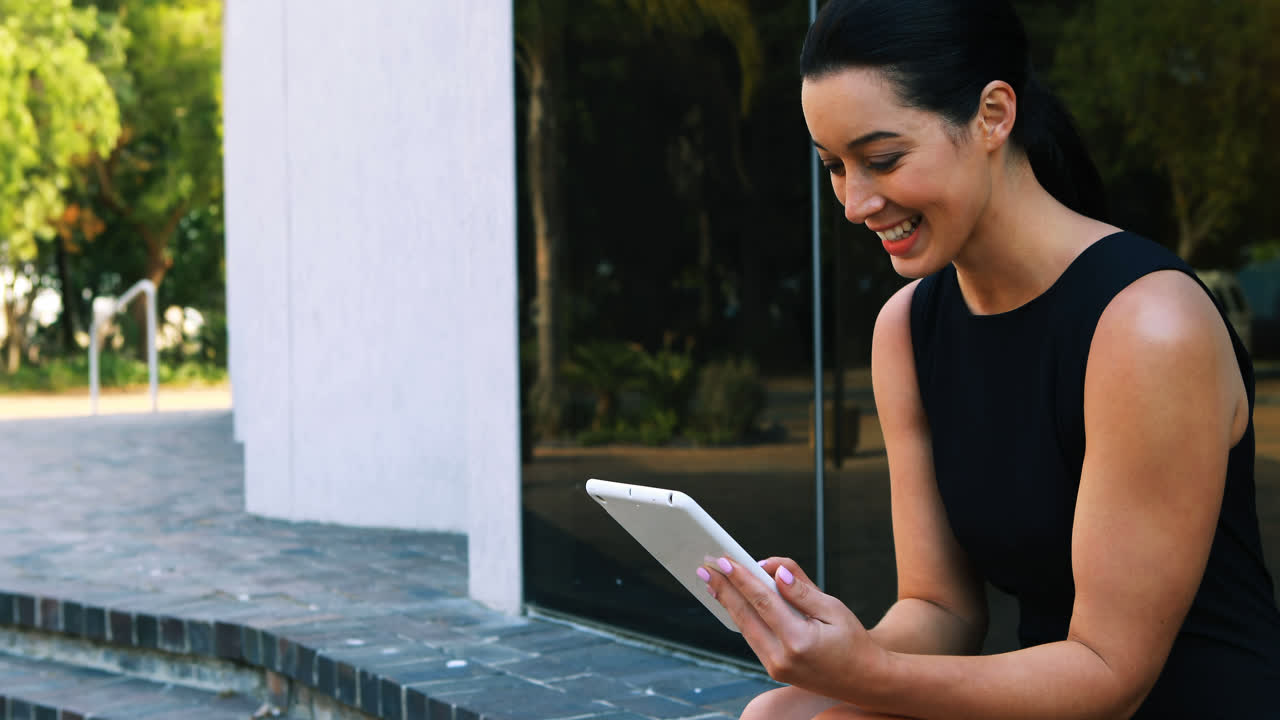 Businesswoman sitting on steps and using digital tablet 4k