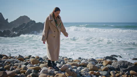 carefree girl walking seashore stepping on beach stones. ocean waves washing