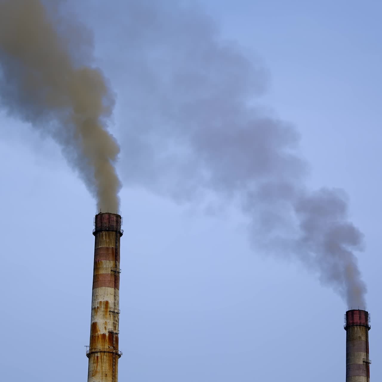 Smoke pouring from two industrial pipes. Factory cocncrete pipes pollute air with smoke