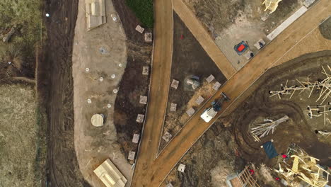 Drohnenaufnahme-Nach-Einem-Bulldozer,-Der-Kies-Auf-Einer-Sonnigen-Parkbaustelle-Bewegt