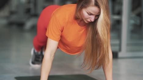 Junge-Hübsche-Frau-Drückt-Sich-Im-Fitnessstudio-Vom-Boden-Ab