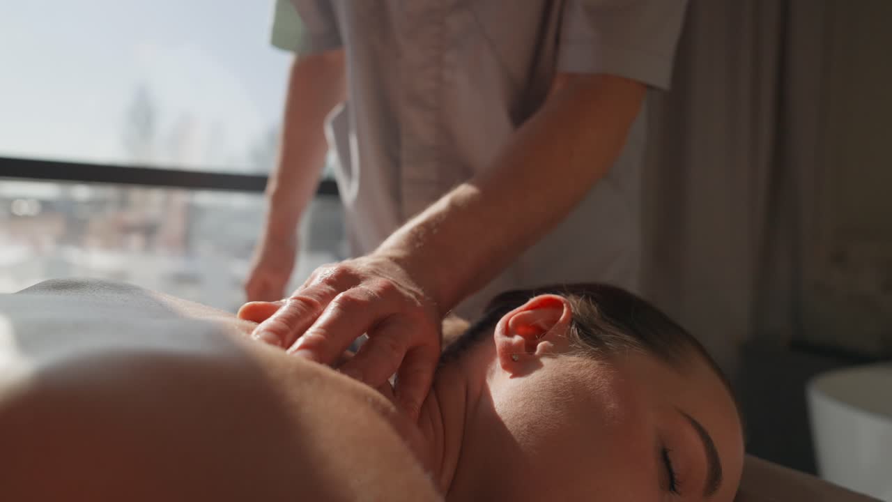 Kvinde får afslappende skulder- og nakkemassage på et spa