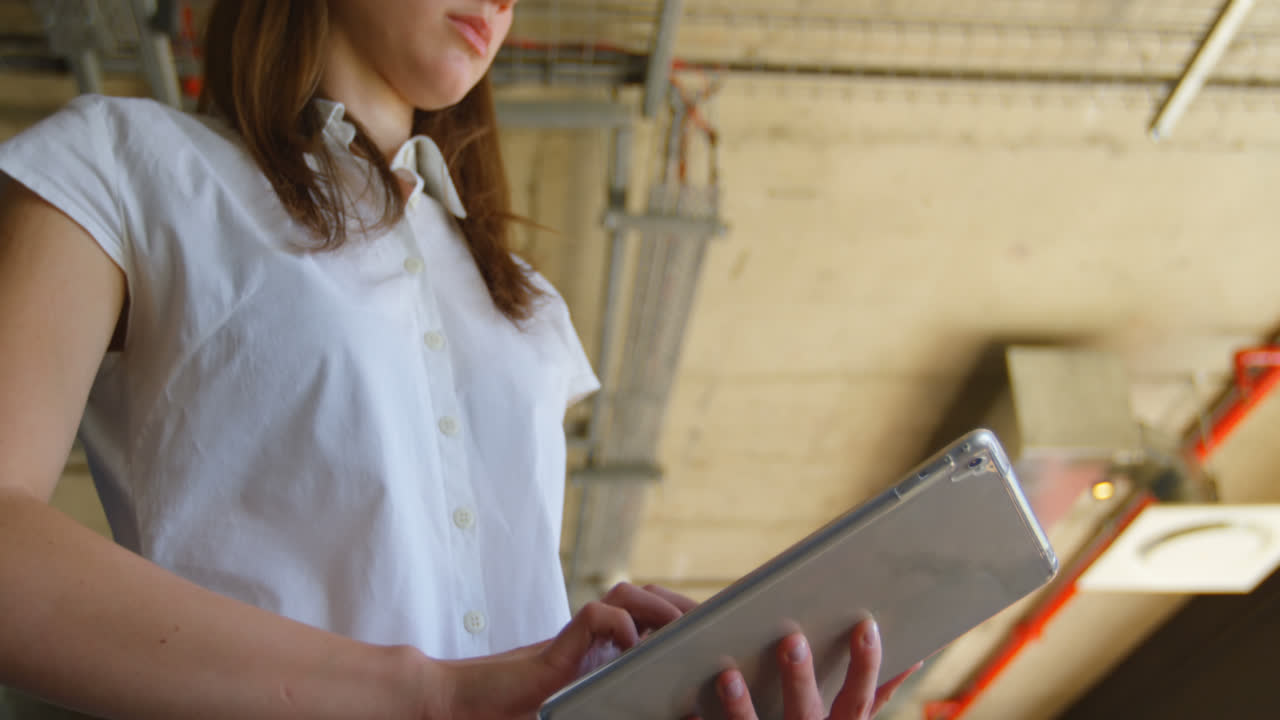 vista de ángulo bajo de una joven mujer de negocios caucásica trabajando en una tableta digital en una oficina moderna 4k