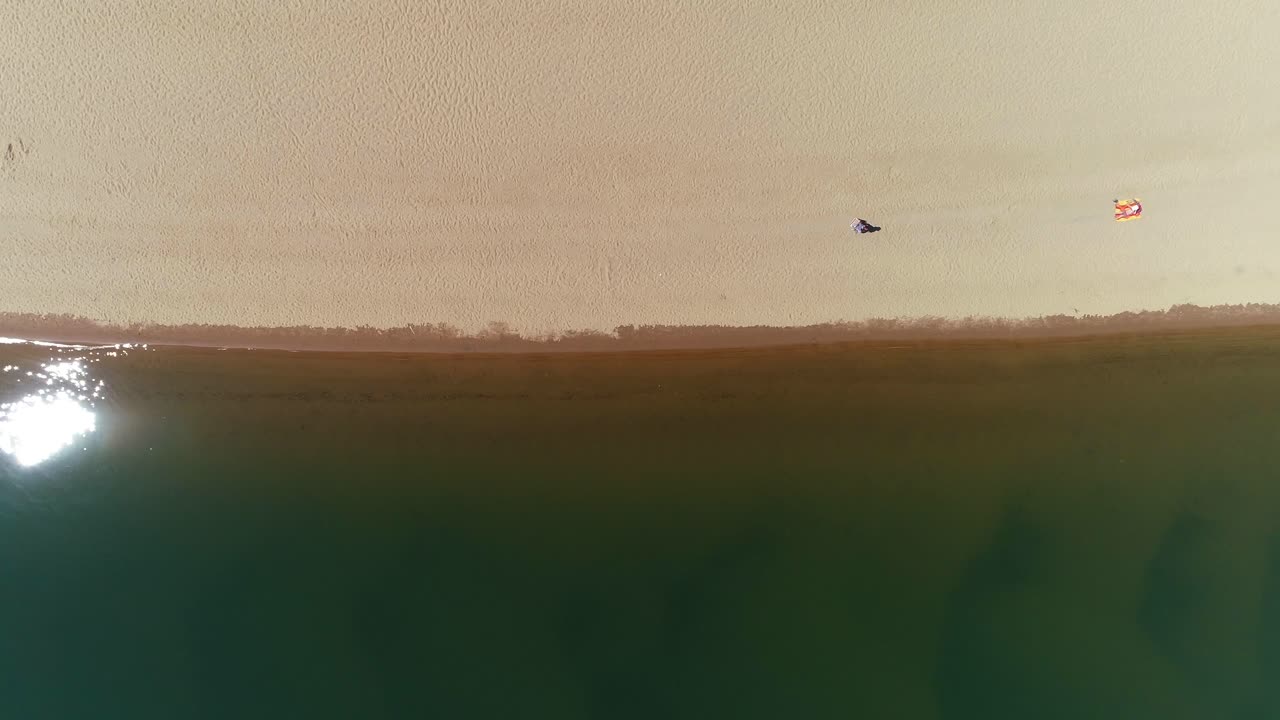 모래 와 대조적 인 조용 한 어두운 물 이 있는 해변 의 공중 풍경