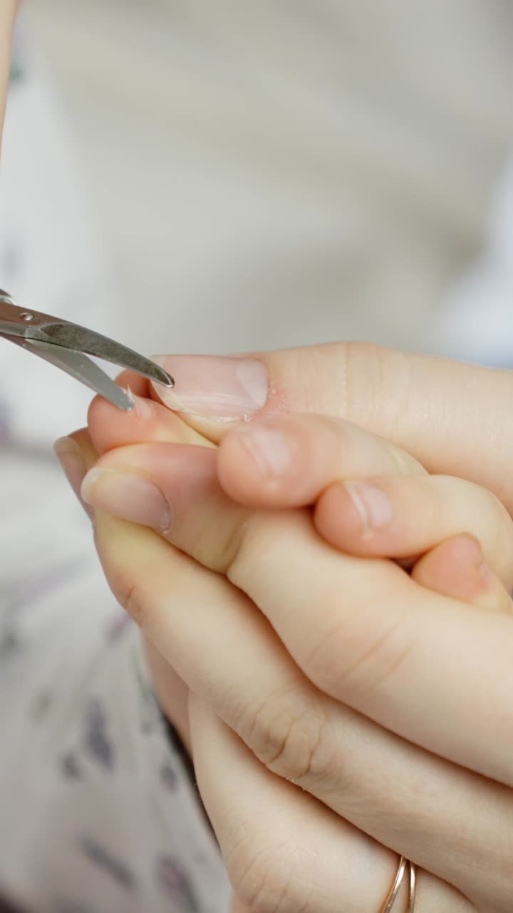 Child Fingers gently held while trimming a fingernail with precision scissors. Captures detail of personal care, grooming, and hygiene in a well-lit vertical close-up shot.