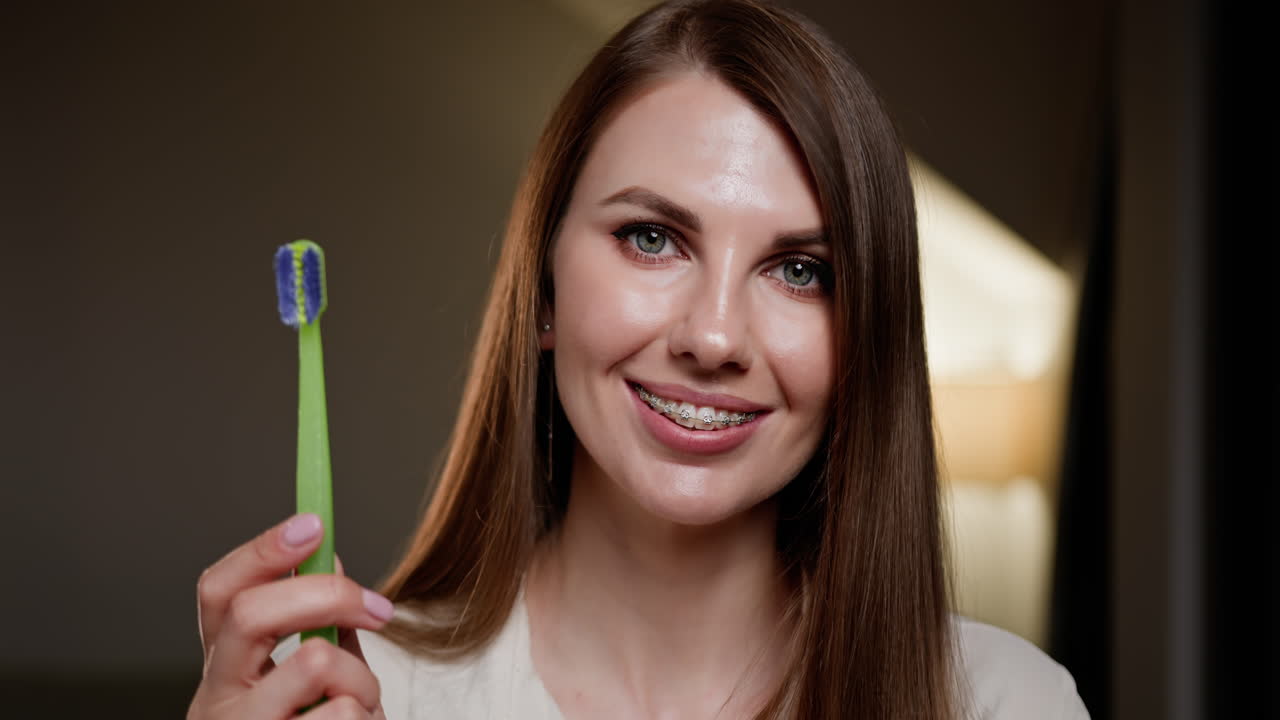 mujer con aparatos ortopédicos sosteniendo un cepillo de dientes