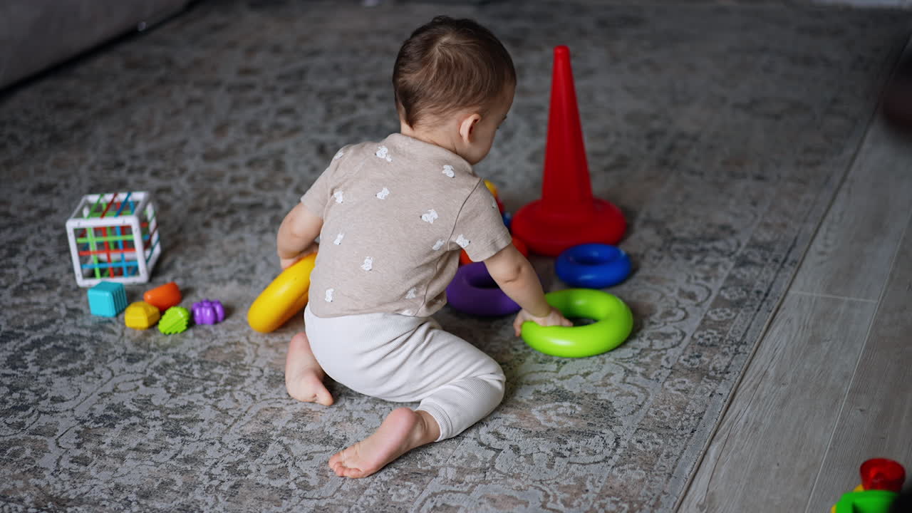 Sweet little baby boy playing with toys on the floor. Lovely toddler assembling pyramid and then crawls up the stairs.