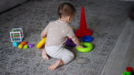 sweet little baby boy playing with toys on the floor. lovely toddler assembling pyramid and then crawls up the stairs.