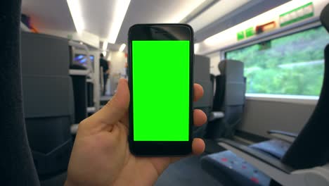 mano sosteniendo un teléfono con una pantalla verde en el tren