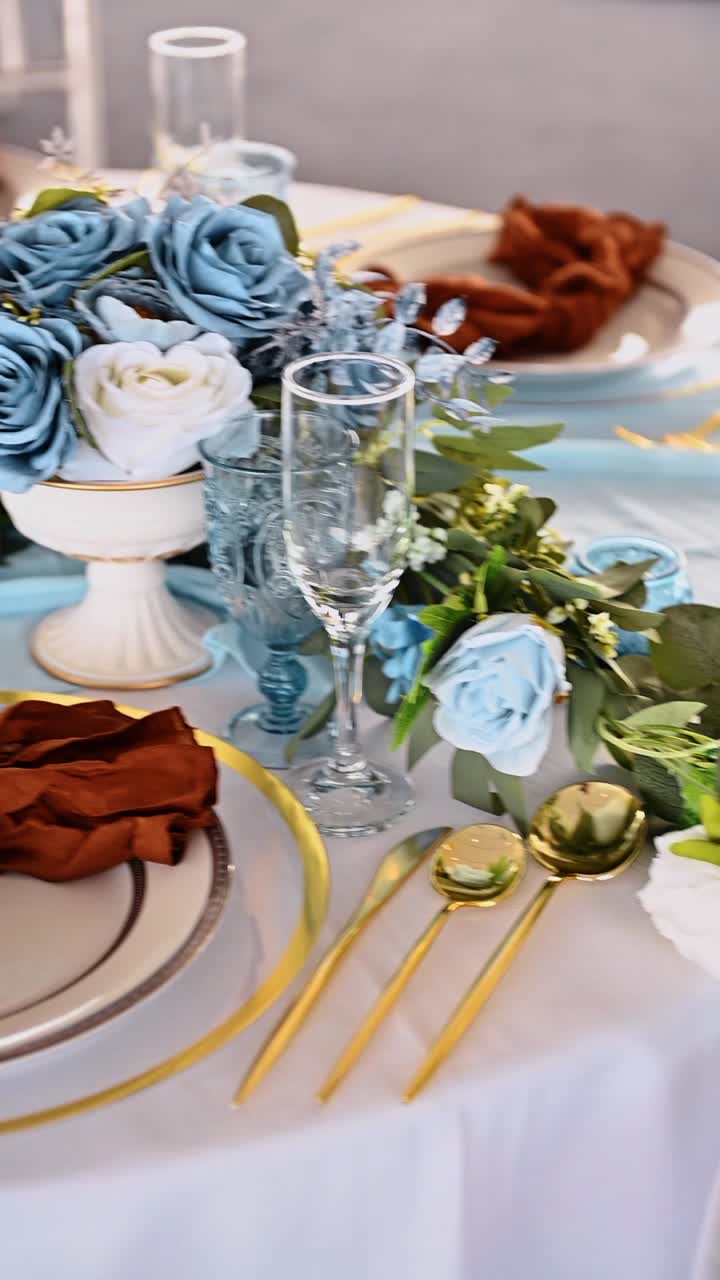 Top view of gold cutlery and blue table decor. Overhead shot of gold forks, spoons, and knives on a light blue runner with a terracotta napkin