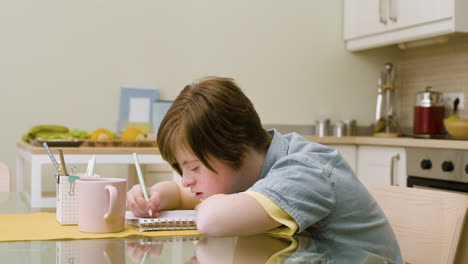 young girl writing on paper in the kitchen