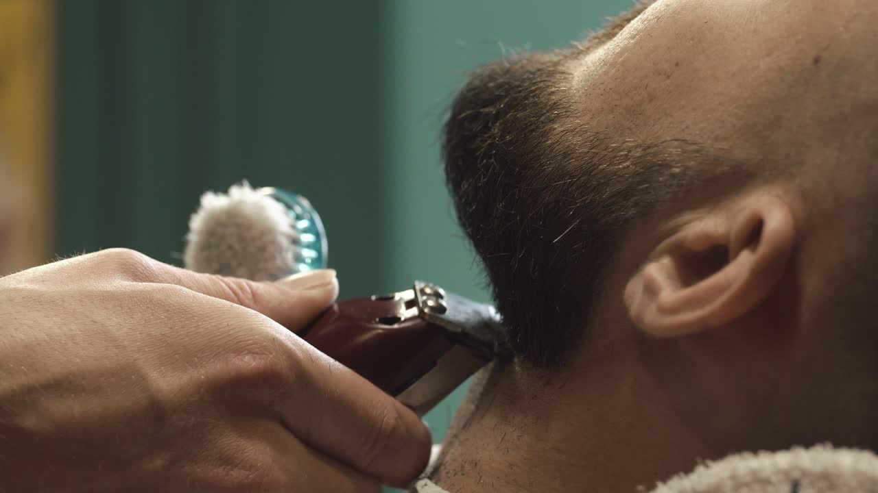 Close-up of a barber trimming a man's beard or neck with an electric shaver