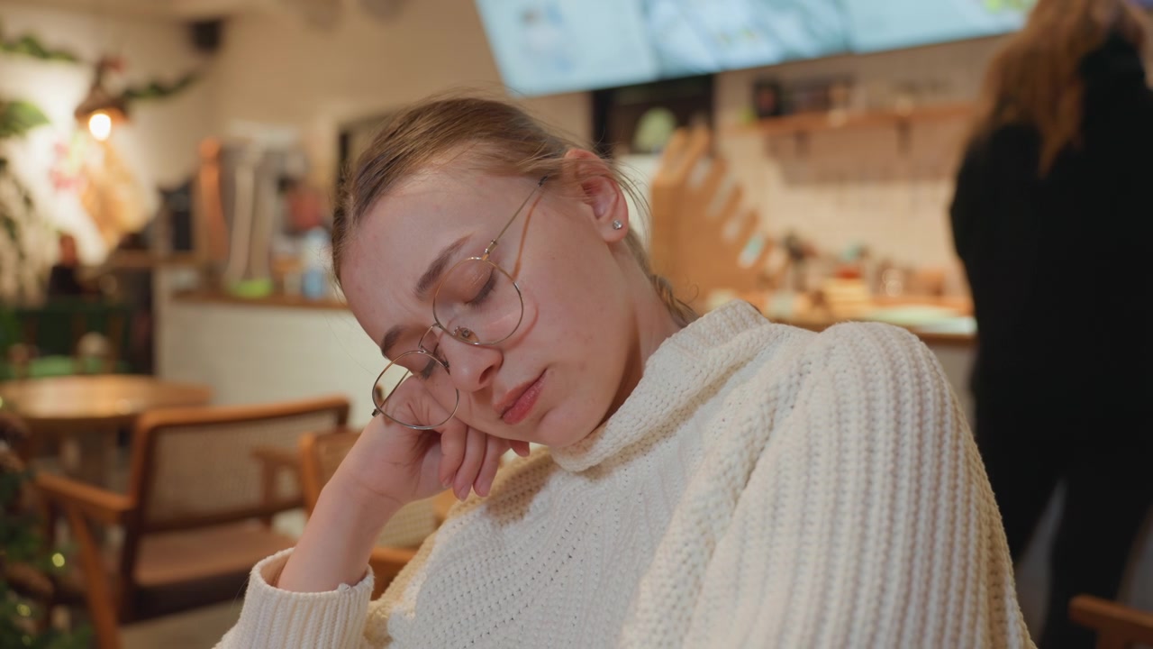 Giovane donna con gli occhiali che riposa serenamente in un caffè