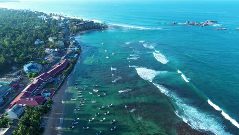 Aerial-drone-landscape-of-coastline-headland-with-charter-boats-docked-near-restaurants-resort-hotels-in-Turtle-beach-bay-in-Hikkaduwa-Sri-Lanka-Asia-travel-holidays