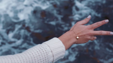 Nahaufnahme-Einer-Frau,-Die-Am-Strand-Mit-Der-Hand-über-Das-Meerwasser-Winkt