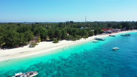 traditional boats anchoring on tranquil turquoise lagoon near shoreline of tropical island with green vegetation and white sandy beach, philippines