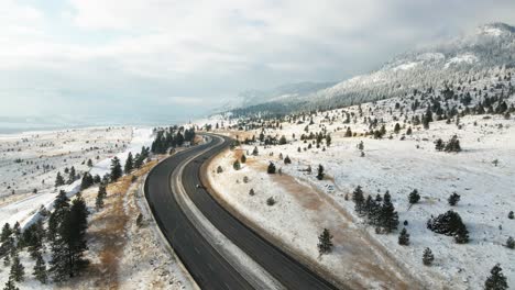 cars driving on the coquihalla highway 5 between merritt and kamloops on a partly cloudy day in the winter, mountain sides covered in snow