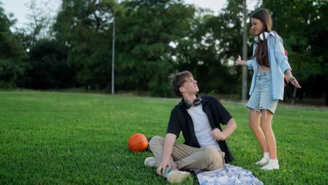 two young people sitting on the grass, laughing and talking.