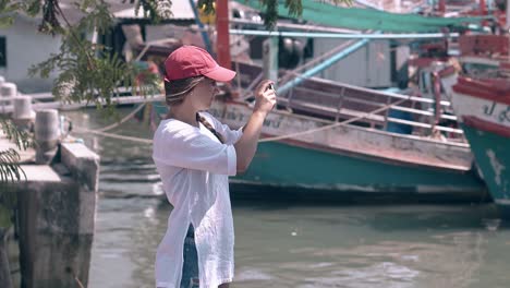 woman in white sari shoots local boats on phone in bay