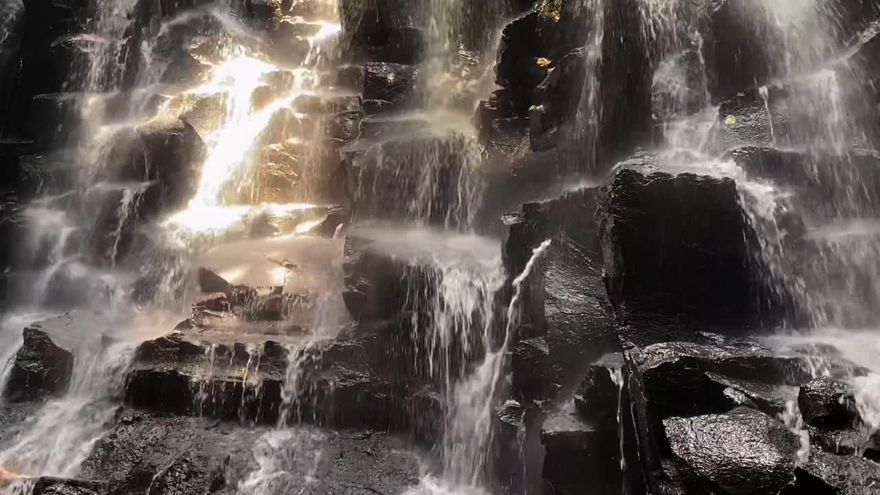 Kanto Lamp Waterfall Cascading Over Rocks with a Tilt Up Panning Shot in Bali, Indonesia.