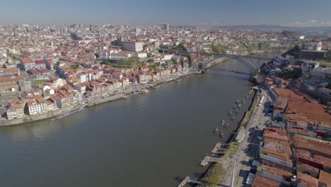 Toma-Aérea-Desde-Una-Plataforma-Rodante-Con-Un-Impresionante-Panorama-Del-Casco-Antiguo-De-Oporto-Con-El-Puente-Ponte-Dom-Luis-I-Sobre-El-Río-Duero.