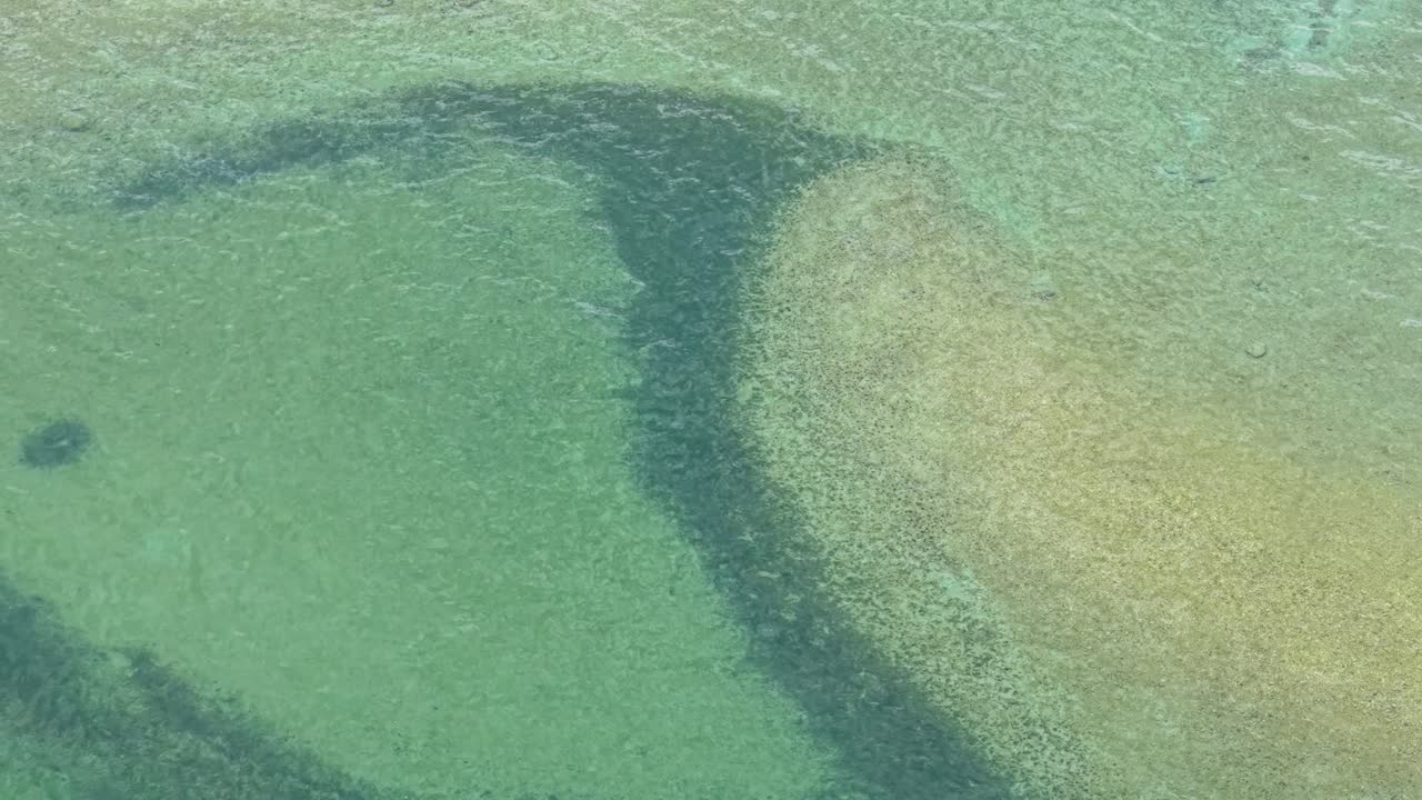 Aerial drone view of shallow Lake Huron waters in Michigan’s Upper Peninsula with visible sandbars and underwater patterns