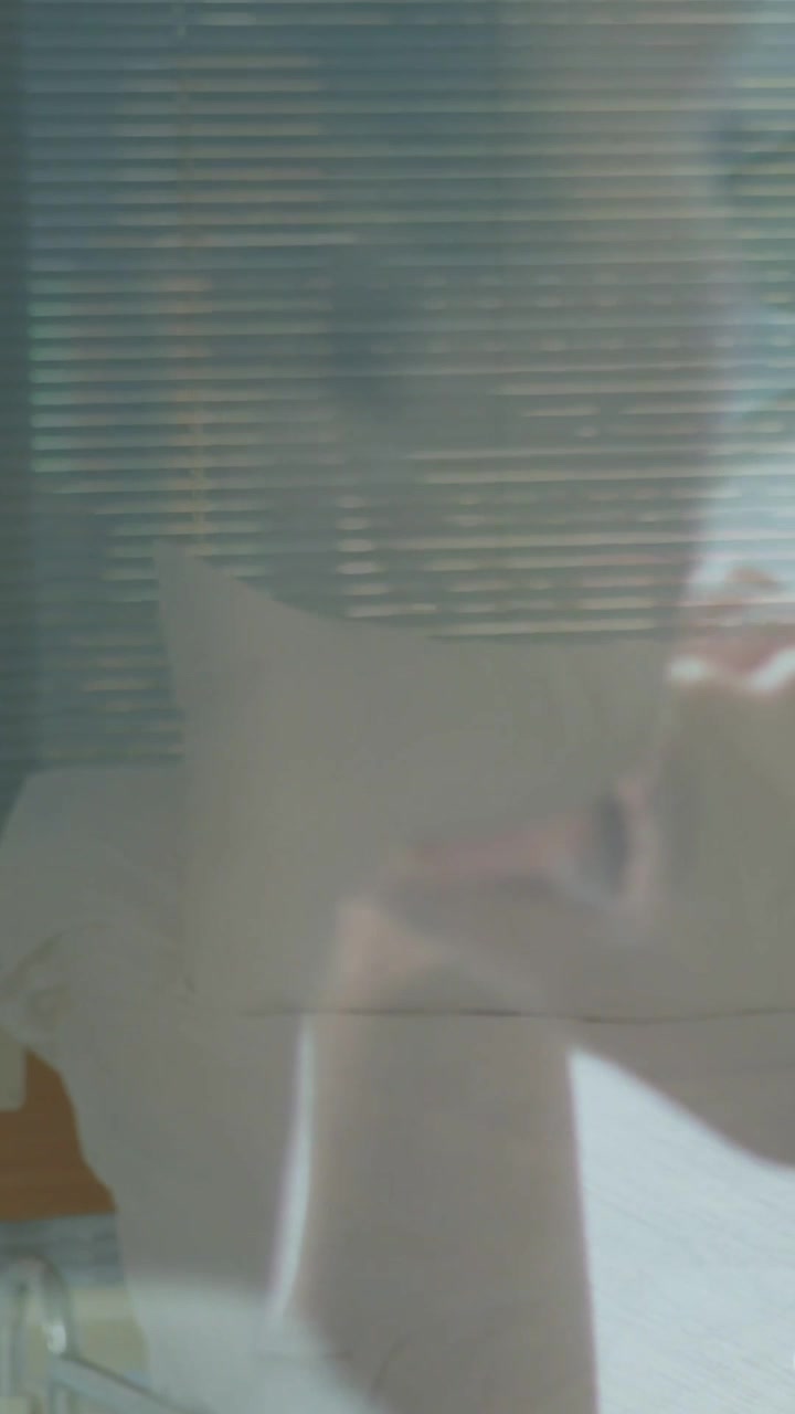 Vertical video: Woman lying on pillow by blinds as overlay emerging, touching face for rest health