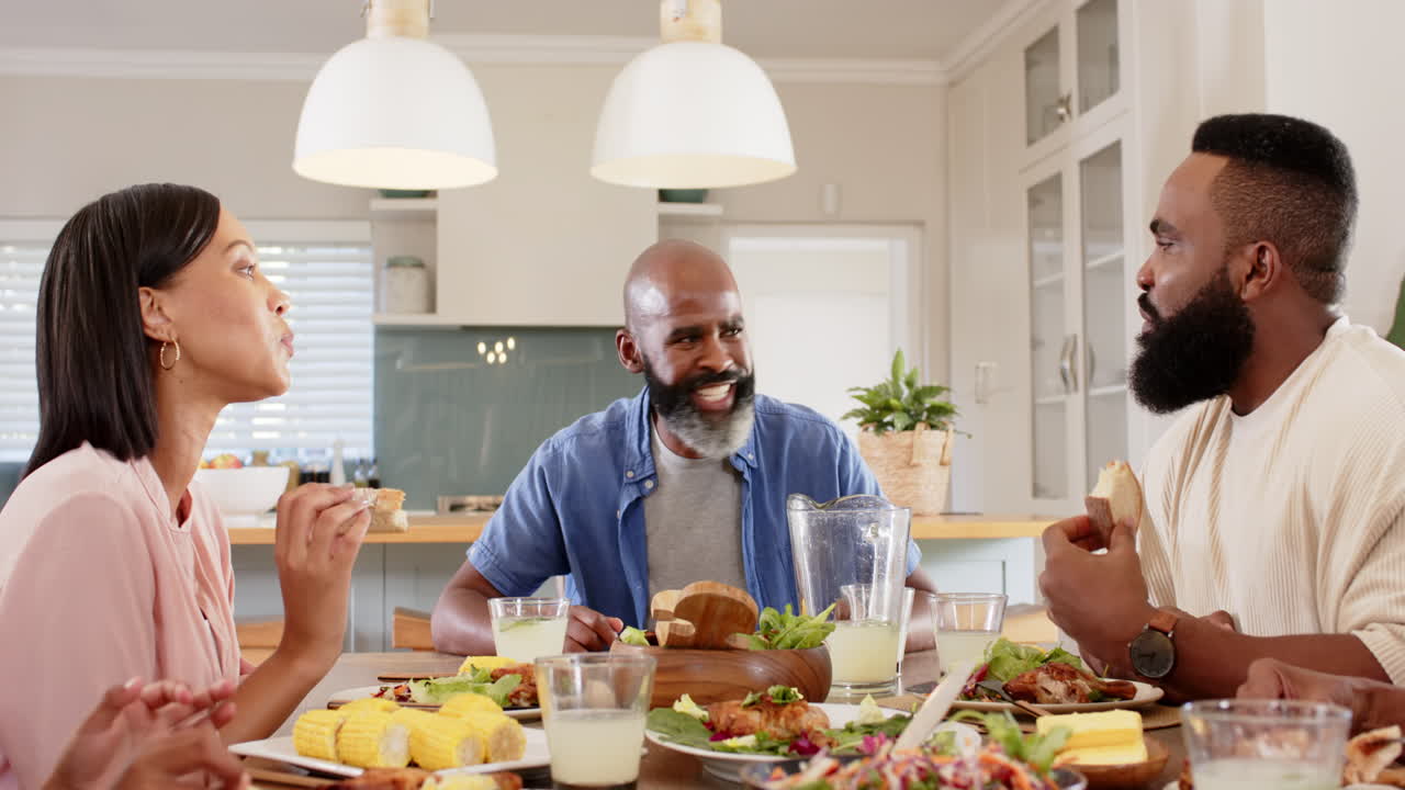 african american family enjoying meal together, laughing and eating in modern kitchen