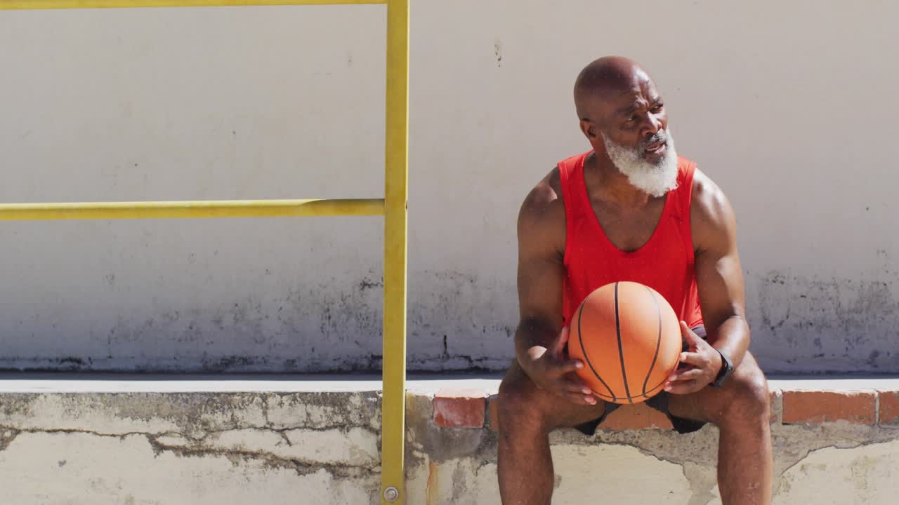 Bearded man sitting on steps with yellow rail holding ball, sun glinting causing animated arc promo