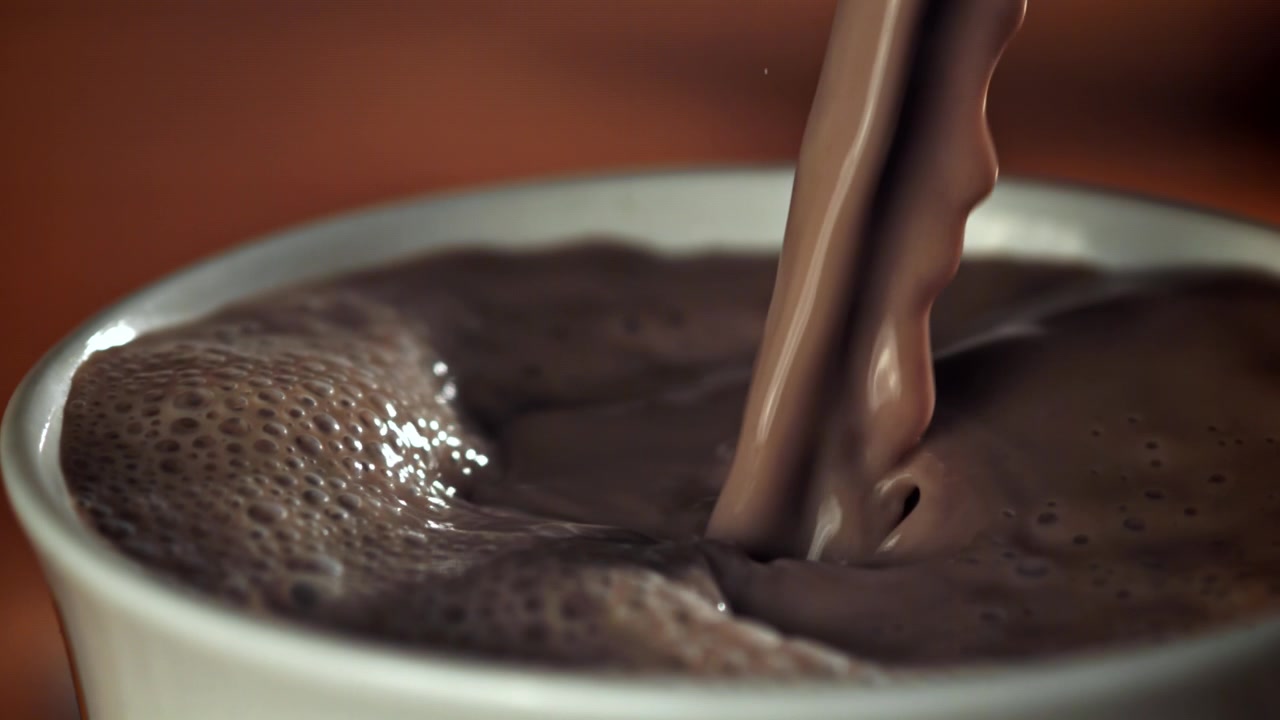 Primo piano di latte al cioccolato versato in una tazza bianca