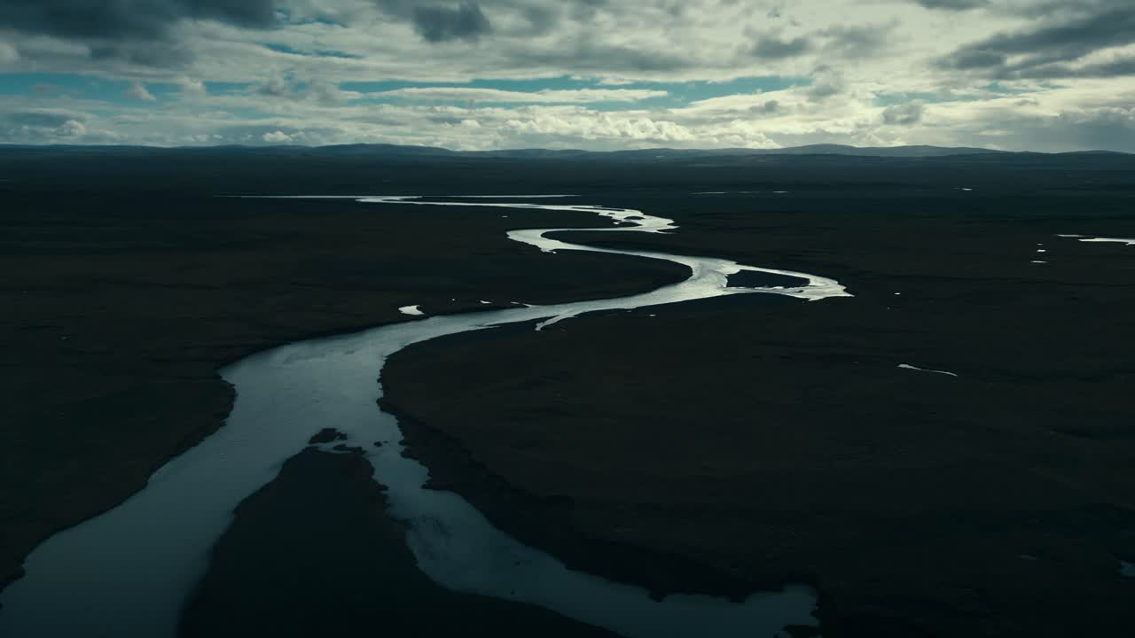 Drone aerial of a twisting snakelike river in the cool dark of the ominous clouds