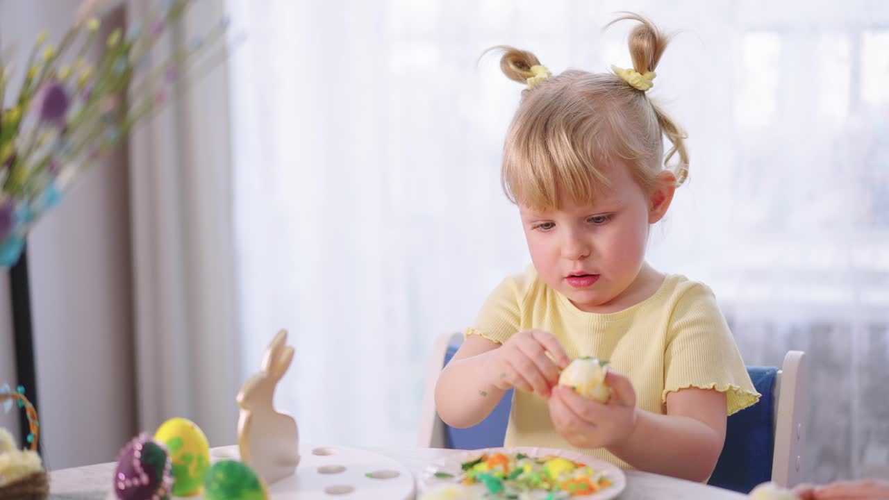 Simpatica bambina che decora un uovo di Pasqua con codette colorate