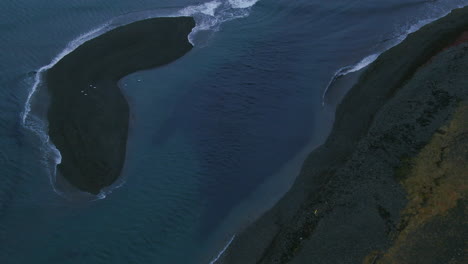 aerial view of waves softly crashing to the shore in iceland