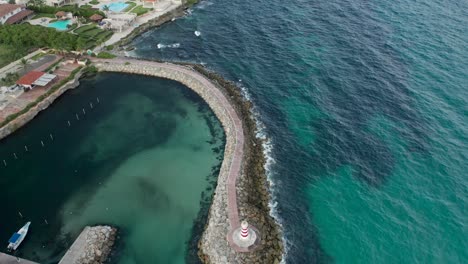 medium shot of drone passing over the lighthouse and the wave breaker