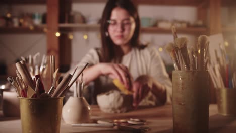 young woman potter working with the clay with her hands and a sponge