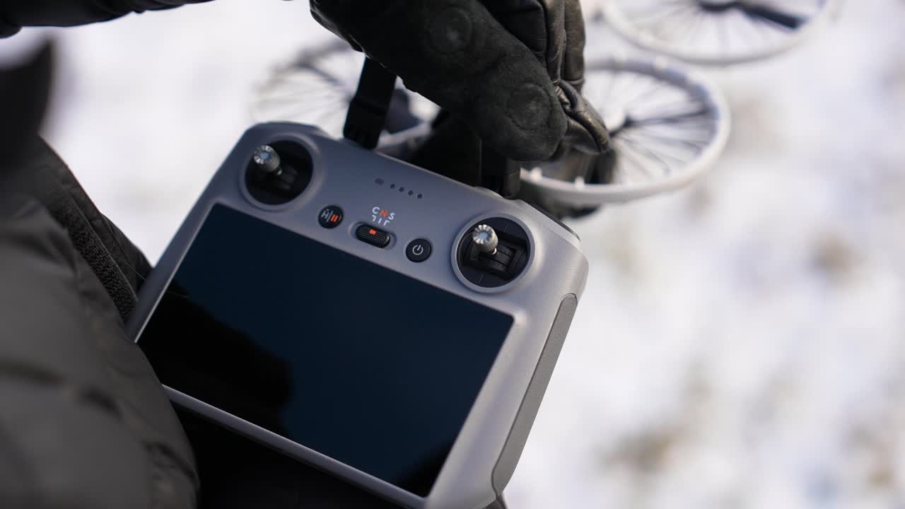 Gloved hands unfolding antennas on drone controller in winter, Czechia