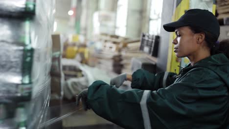 and african-american woman in a special green uniform monitors the process of packaging raw materials at a waste processing plant