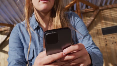 video of happy caucasian female skateboarder resting and using smartphone