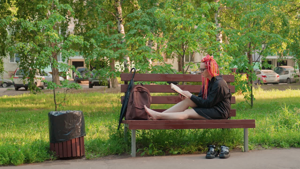 Летнее чтение для души: девушка наслаждается солнечным парком с книгой, молодая женщина неспешно читает босиком на скамейке в парке, расслабленная девушка принимает солнечные ванны и увлеченно читает книгу в солнечный день в парке