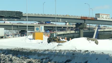 loader clearing the snow in the road with traffic in the distance at winter in montreal, canada