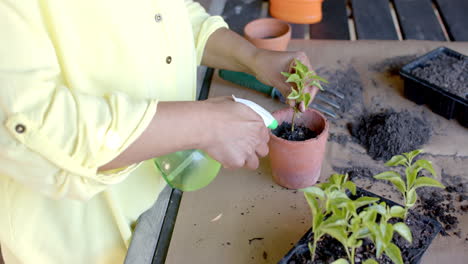 Mujer-Birracial-Mayor-Regando-Plantas-En-Macetas-En-El-Jardín-De-Casa,-Cámara-Lenta