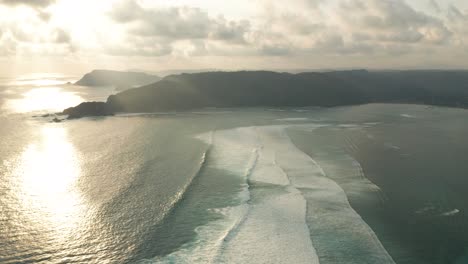 Tranquilas-Líneas-De-Olas-Llegan-A-La-Bahía-De-Laut-Lombok-Durante-La-Puesta-De-Sol,-Antena