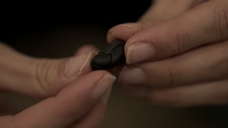 close up shot of a girl hands touching and breaking a cocoa bean